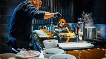 man in blue jacket pouring water on white ceramic bowl