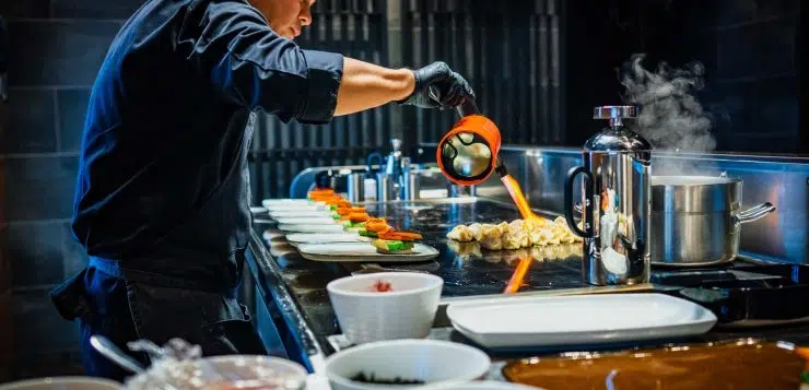 man in blue jacket pouring water on white ceramic bowl